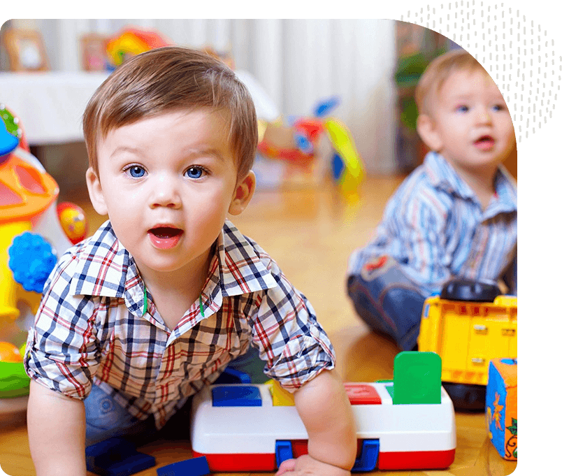 Two young boys playing with toys on the floor.