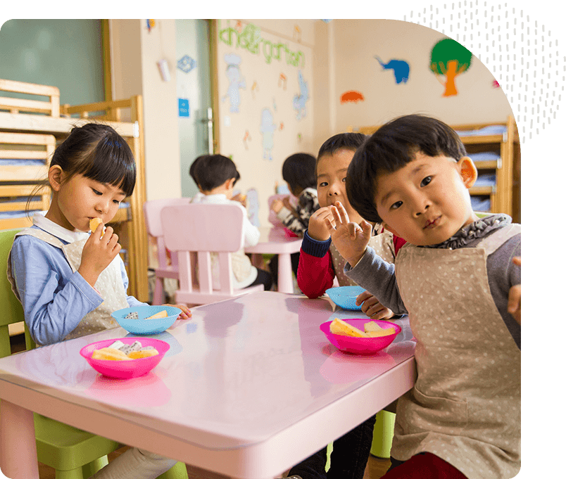 A group of children eating food at a table.